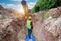 Engineer wear safety uniform examining excavation Drainage Pipe and Large plumbing water system underground at construction site