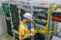 The engineer in a white helmet measures the level of the optical signal in the server room of the data center. A technician