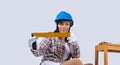 Engineer woman in a blue hard hat and gloves holds a level, a ruler on a white background with side space. Royalty Free Stock Photo