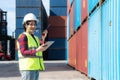 Engineer woman or Foreman manager in container depot working with digital tablet and walkie talkie for control and checking