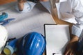 Engineer work desk concept. White and blue Safety hard hat on the blueprint with contract folder as background Royalty Free Stock Photo