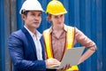 Engineer worker or technical women standing with her boss in the container yard shipping area. A man holding a laptop and discuss