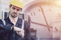Engineer worker worry looking at wristwatch overlay time clock face. Industry factory late working hours concept Royalty Free Stock Photo