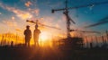 Engineer workers standing on a construction site and watching the sunset with building silhouettes in the background Royalty Free Stock Photo