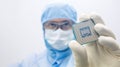 An engineer working in a clear room wearing a special uniform and protective glasses hold processor cpu by hand in glove Royalty Free Stock Photo