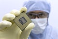 An engineer working in a clear room wearing a special uniform and protective glasses holds processor cpu in hand in Royalty Free Stock Photo