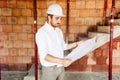 engineer working on site, man reading paper plans and supervising works Royalty Free Stock Photo