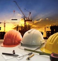 engineer working table plan, home model and writing tool equipment against building construction crane with evening dusky sky Royalty Free Stock Photo