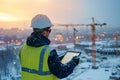 Engineer working with tablet on construction site at sunset