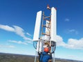 Engineer working on a telecommunications tower against the background of the blue sky. Royalty Free Stock Photo