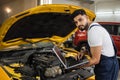 Engineer young man looking at inspection vehicle details under car hood Royalty Free Stock Photo