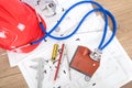 On engineering drawings and drawings, a hard hat and other related tools with a stethoscope being auscultated a small house model Royalty Free Stock Photo