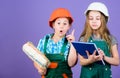 Engineering idea. small girls repairing together in workshop. Labor day. 1 may. Little kids in helmet with tablet and