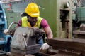 Engineering male African American wear hardhat working at machine in factory. Man technician control metalwork lathe industrial.