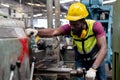 Engineering male african american wear hardhat working at machine in factory. Man technician control metalwork lathe industrial.