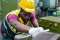 Engineering male african american wear hardhat working at machine in factory. Man technician control metalwork lathe industrial.