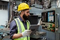 Engineering male workers wear yellow helmet holding tablet working at operating machine. Royalty Free Stock Photo