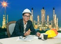 Engineering man working on table against beautiful lighting of oil refinery plant Royalty Free Stock Photo