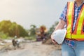 Engineering woman holding a white safety helmet standing In front of the construction site. Concepts for controlling and checking Royalty Free Stock Photo