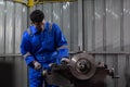Engineering worker man African American wearing uniform safety working machine lathe metal brake disc grinder in factory