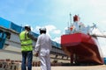 Engineering Workers planning hand holding blue print of the commercial ship standing on floating dry dock yard Royalty Free Stock Photo