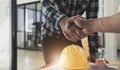 Engineers or architecture shaking hands at construction site for architectural project, holding safety helmet on their Royalty Free Stock Photo