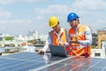 Engineers discussing project of solar power station with laptop computer. Solar panel technician on roof. Engineer and Young Royalty Free Stock Photo