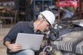 Engineers holding laptop computer in the factory. A skilled mechanic inspecting auto parts in a factory