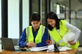 Engineers man and woman wearing yellow vests working with blueprint, discussing the new project at office Royalty Free Stock Photo