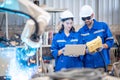 Engineers mechanic using computer controller Robotic arm for welding steel in steel factory workshop