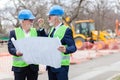 Engineers meeting and discussing blueprints while visiting work site