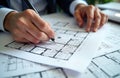 Engineers review building plans. Hands adjust details on floor plans. Building specifications held. Teamwork in progress during