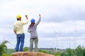 Engineers stand holding blueprints and congratulate wind turbine projects to generate electricity and check wind direction Royalty Free Stock Photo