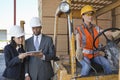 Engineers using tablet PC with female industrial worker driving forklift truck Royalty Free Stock Photo