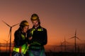 Engineers working on wind turbines farm at sunset,