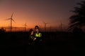 Engineers working on wind turbines farm at sunset,