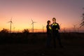 Engineers working on wind turbines farm at sunset,