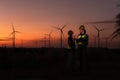 Engineers working on wind turbines farm at sunset,