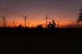 Engineers working on wind turbines farm at sunset,