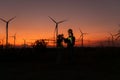 Engineers working on wind turbines farm at sunset,