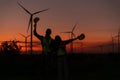 Engineers working on wind turbines farm at sunset,