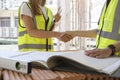 Engineers in yellow vests shaking hands while working at construction site. Building construction collaboration concept Royalty Free Stock Photo