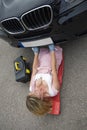 Female mechanic on a crawler to access underside of a automobile.