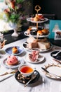 English afternoon tea set including hot tea, pastry, scones, sandwiches and mini pies on marble top table