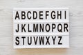 English alphabet on lightbox over white wooden background, overhead view. Letters from A to Z. Back to school concept. From above,