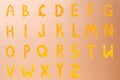 English alphabet of yellow letters made of sunflower petals on a beige shiny background