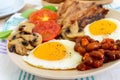 English breakfast: eggs, bacon, beans in tomato sauce, mushrooms, tomatoes, toast with cream cheese and a cup of coffee Royalty Free Stock Photo