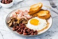 English breakfast with fried egg, bacon, beans, mushrooms and toast on a plate on the table.  Close-up Royalty Free Stock Photo