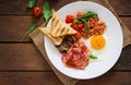 English breakfast - fried egg, beans, tomatoes, mushrooms, bacon and toast.