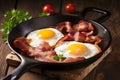 English breakfast, fried eggs, bacon, on a black background. Royalty Free Stock Photo